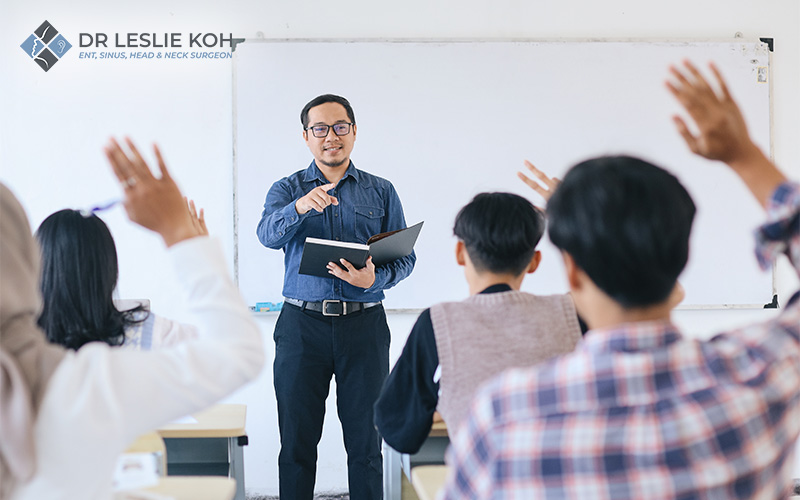 Male teacher engaging students in a classroom setting.