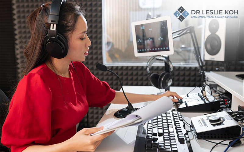 Woman in red dress recording voice in a soundproof studio.