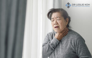 old lady holding her neck seemingly in pain