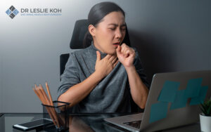 woman touching her throat and coughing