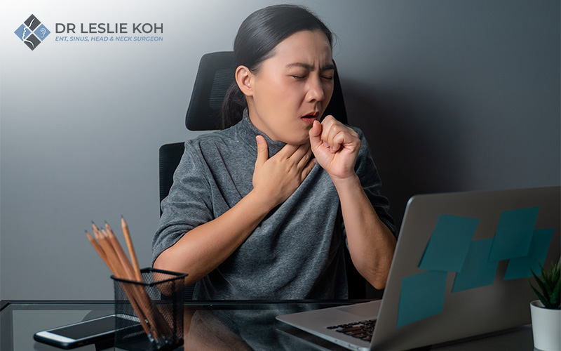 woman touching her throat and coughing
