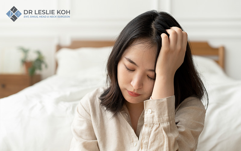 woman seemingly under discomfort holding her head