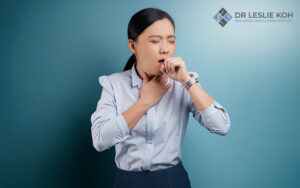 woman coughing and holding her throat.