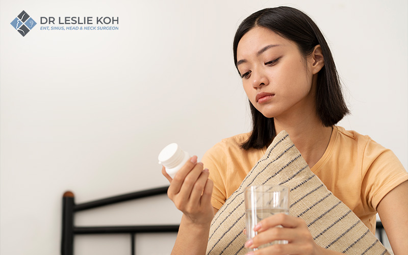 woman holding a glass of water examining a container of medicine.