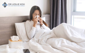 Woman blowing nose from rhinitis or sinus infection.