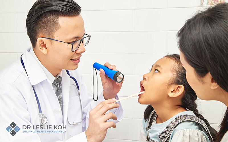 little girl getting her throat checked by an ENT doctor.