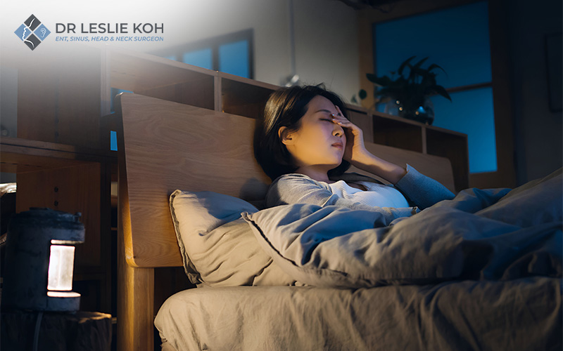 woman having a hard time sleeping leaning on headboard