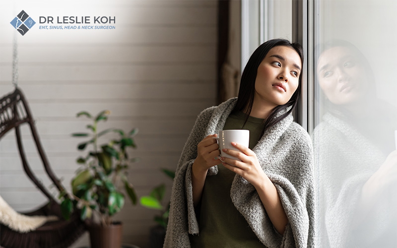 woman wrapped in a blanket, warming up with a hot drink