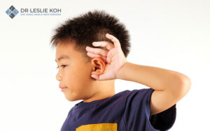 child with his hand on his ear