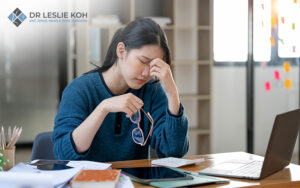 stressed woman working in front of laptop pressing her nosebridge